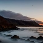 Coastal Sunset with Waves and Majestic Mountains