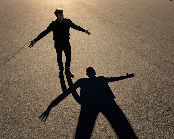 Man with outstretched arms on empty pavement at dawn