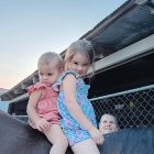 Young girls on unicorn statue in rose field