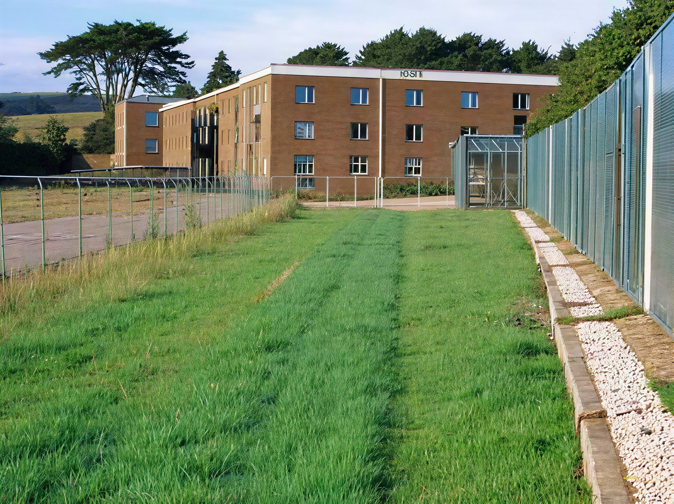 Brick Building with White Frames and Greenhouse Nearby