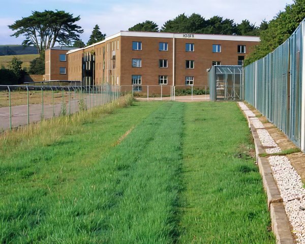 Brick Building with White Frames and Greenhouse Nearby