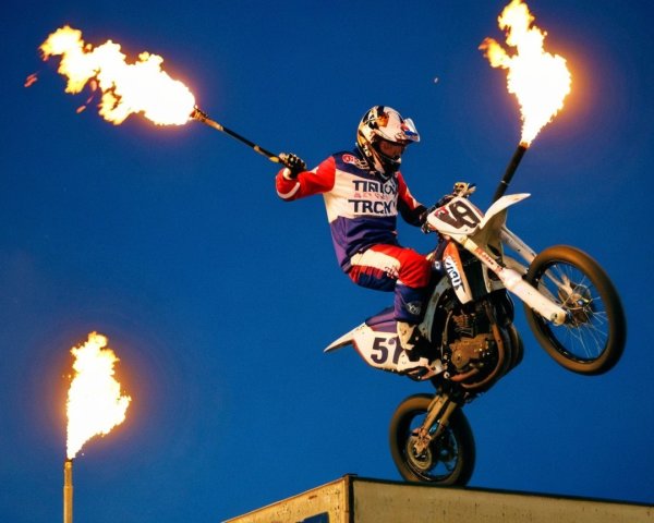 Motocross Rider Performs Stunt with Fire Torches