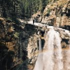 Waterfall Cascading Down Rocky Cliffs with Lush Greenery