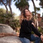 Elegant Woman in Chic Outfit Surrounded by Greenery