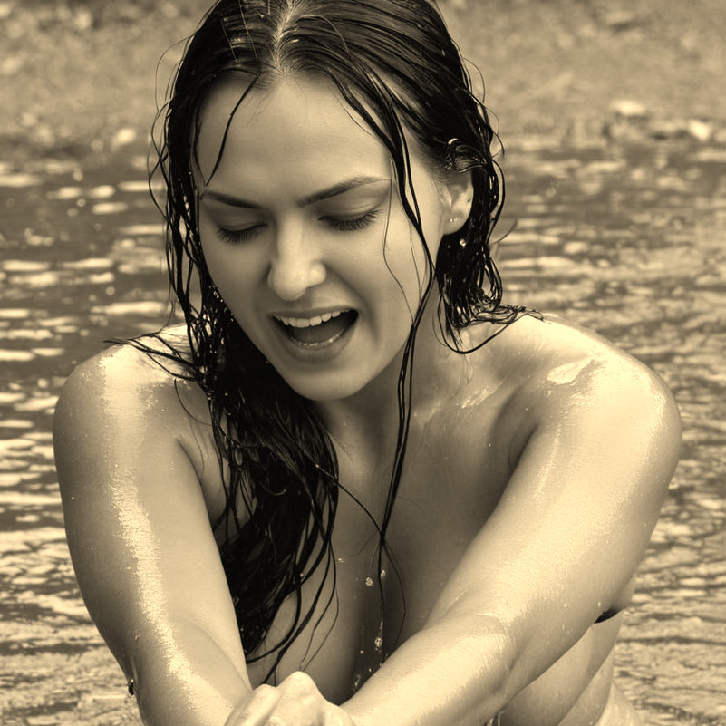 Joyful Woman Splashing in Shallow Water in Sepia Tone