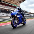 Rider in Black Gear on Blue Motorcycle at Racetrack