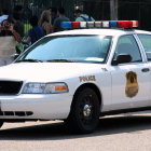 White Police Car with Emblem and Light Bar in City