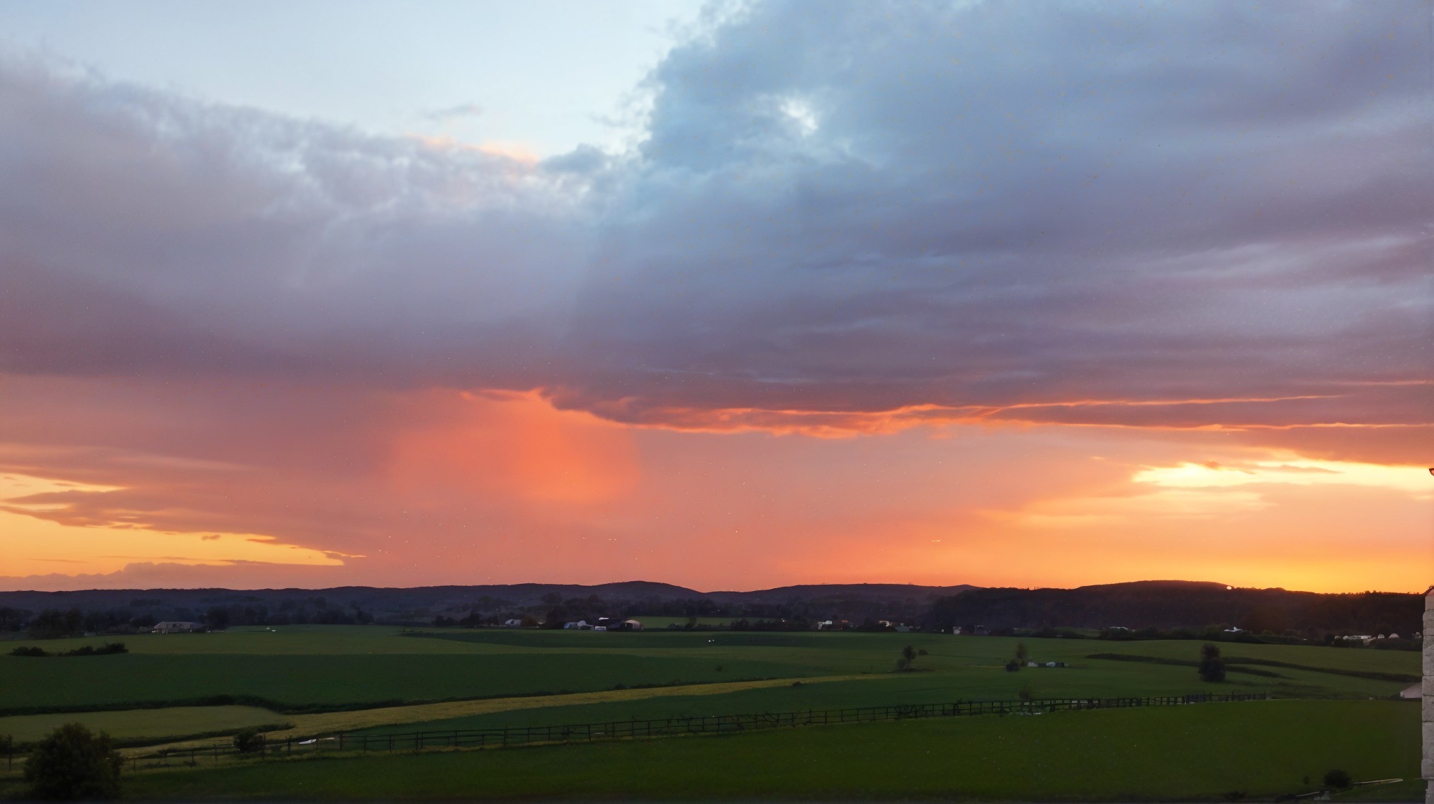 Vibrant Sunset Over Lush Green Landscape and Hills