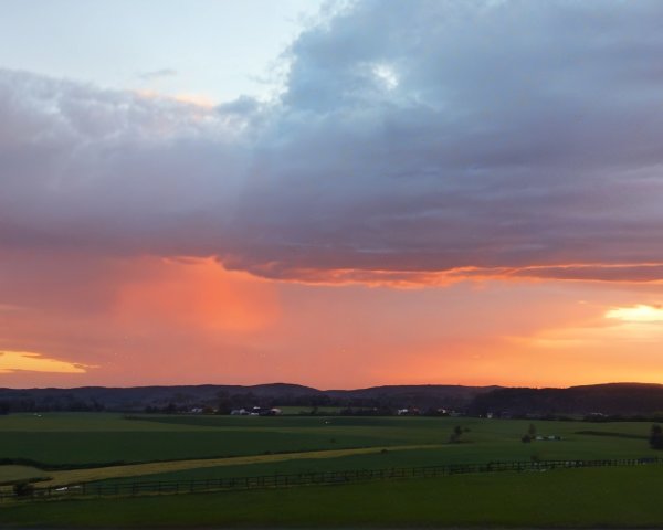 Vibrant Sunset Over Lush Green Landscape and Hills
