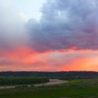 Vibrant Sunset Over Lush Green Landscape and Hills