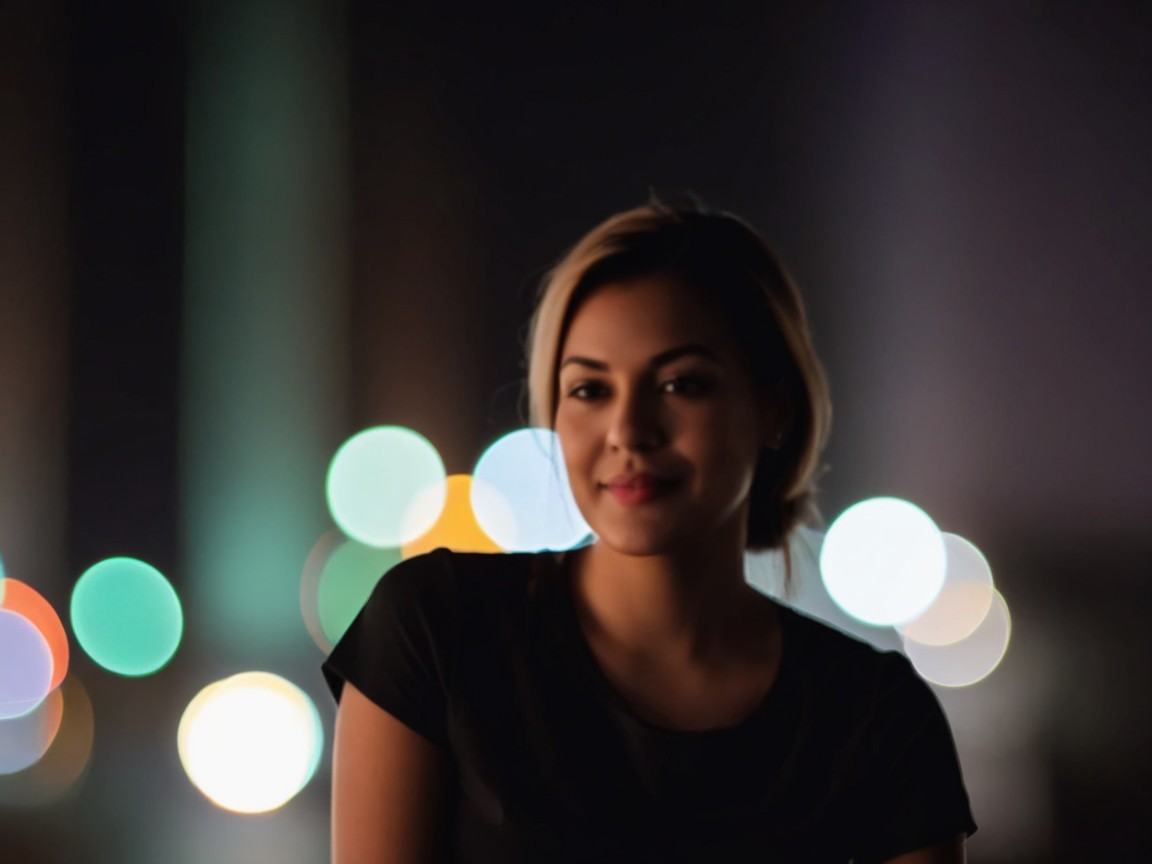 Young woman smiling with city lights in background