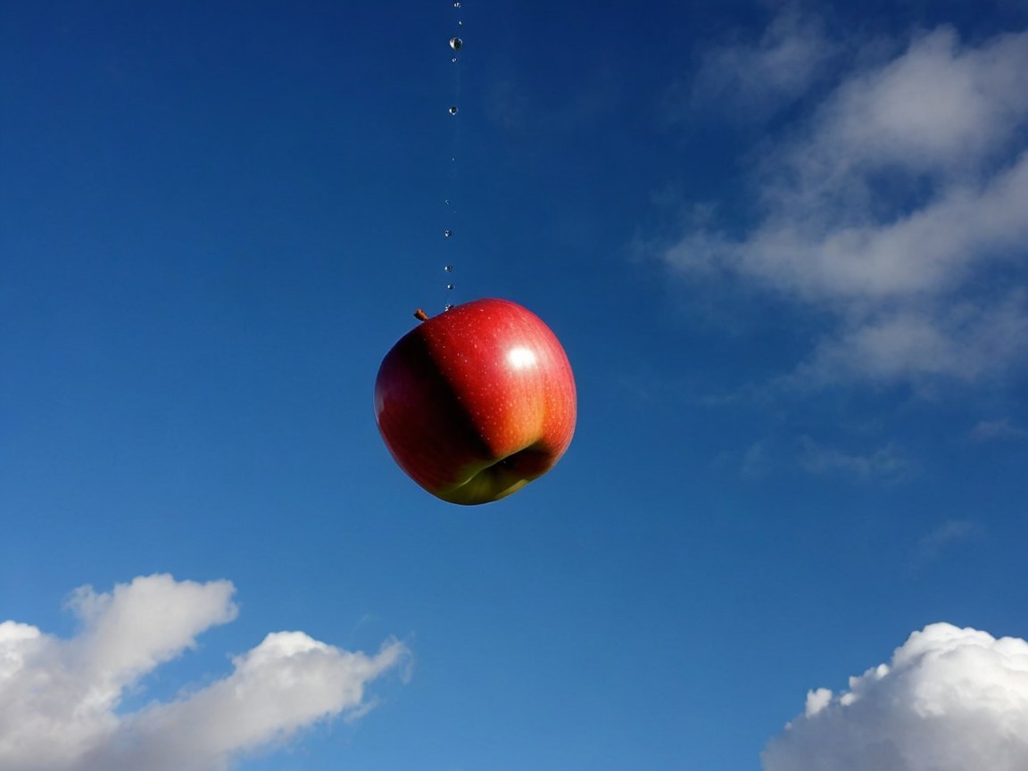 Vibrant Red Apple Against Clear Blue Sky and Clouds