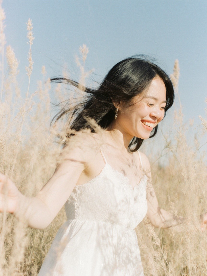 Joyful woman in white dress in sunlit field