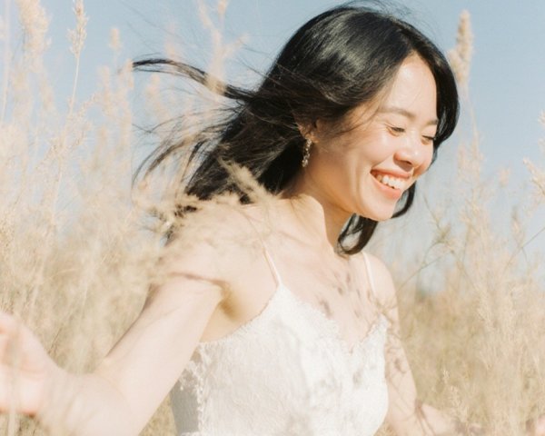 Joyful woman in white dress in sunlit field