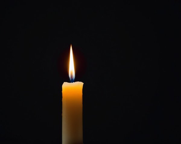 Solitary Candle Against Dark Backdrop with Flickering Flame