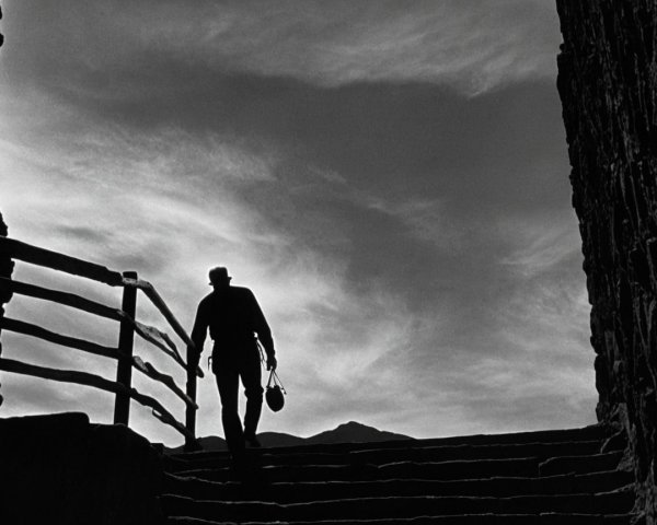 Silhouetted Figure Descending Staircase Against Sky