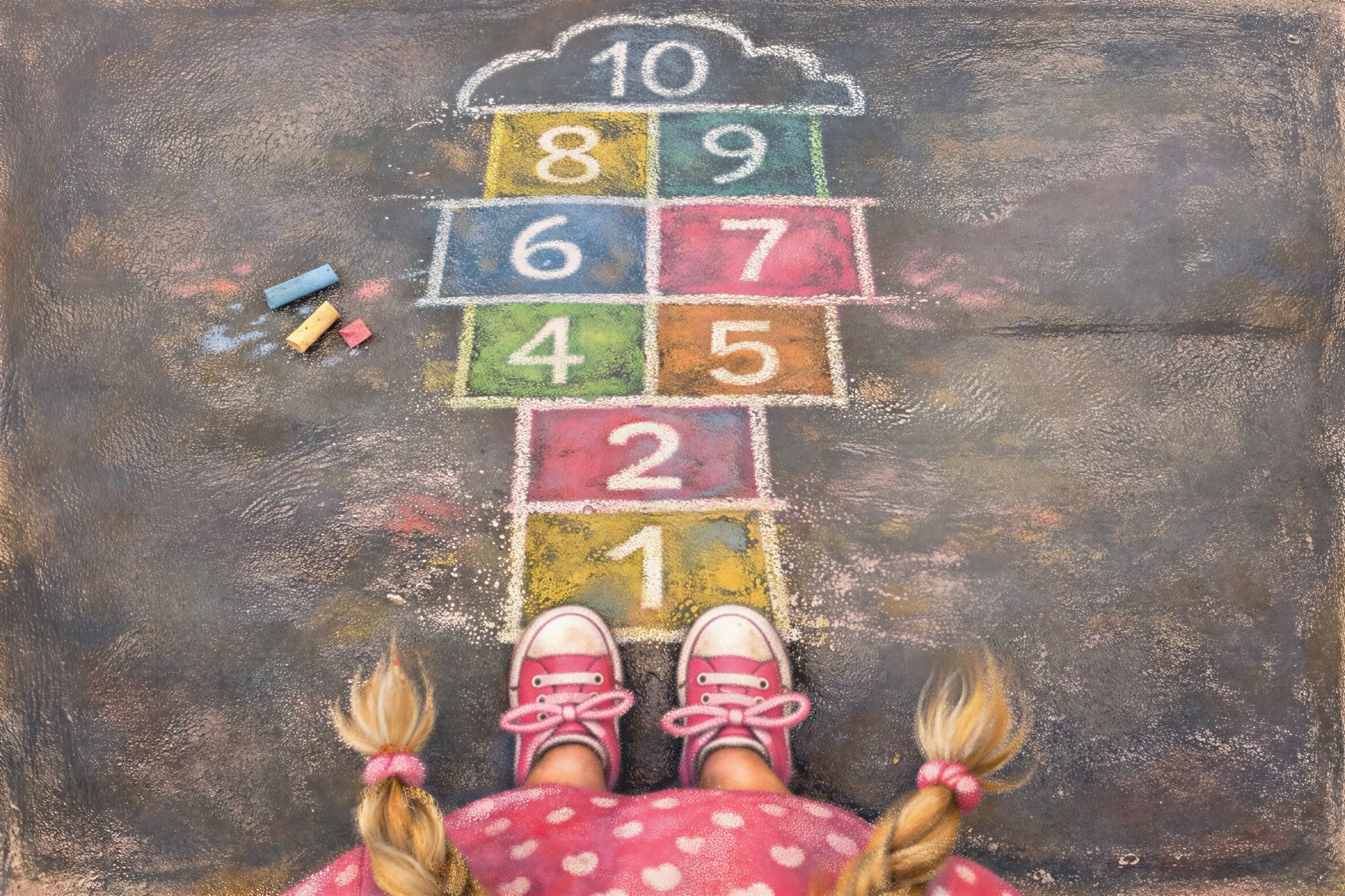 Young girl at colorful hopscotch grid on asphalt