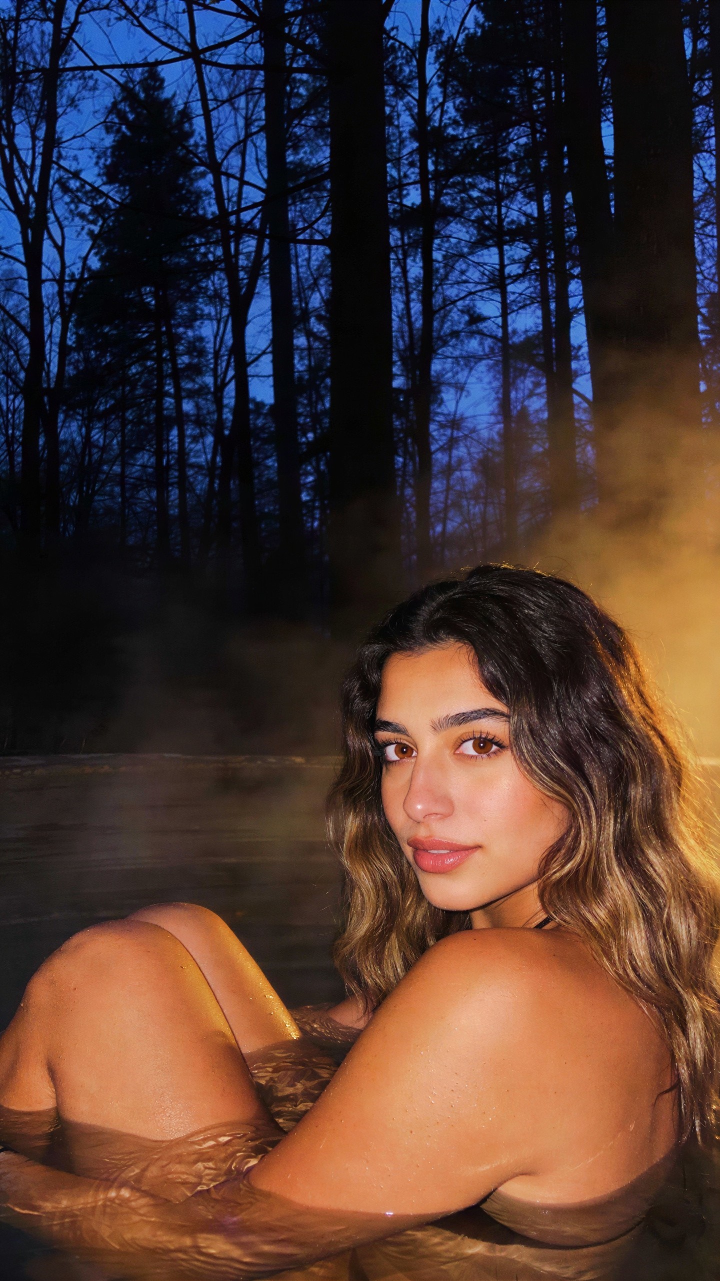 Girl in hot tub at night with steam and silhouettes