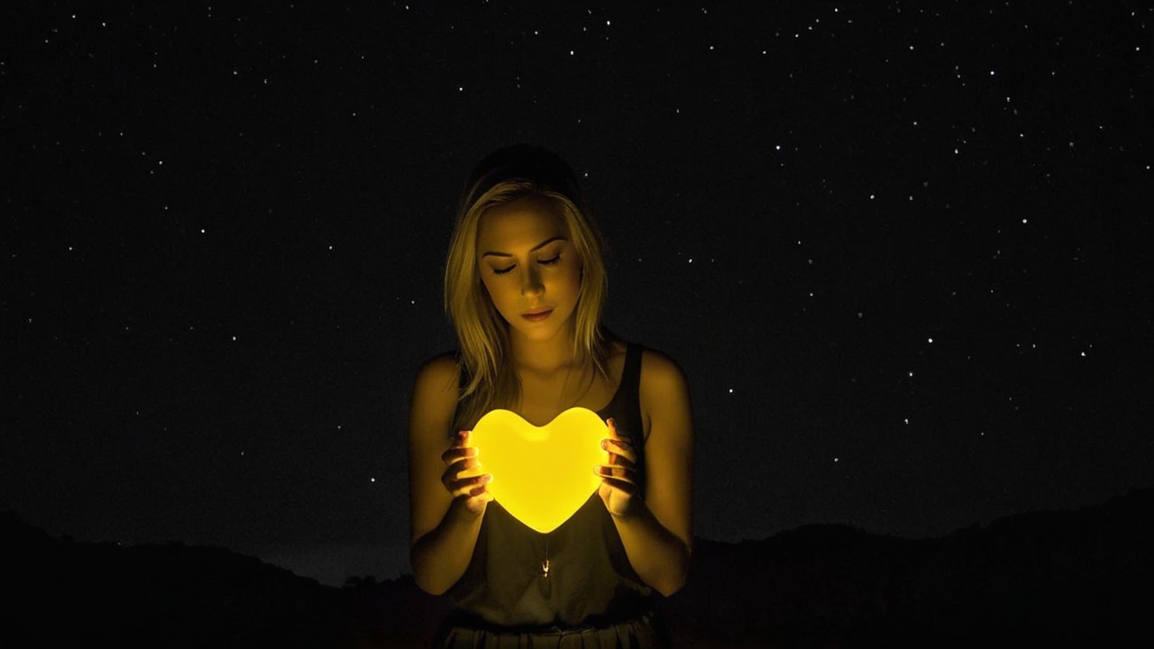 Woman with Heart-Shaped Light in Dark Outdoor Setting
