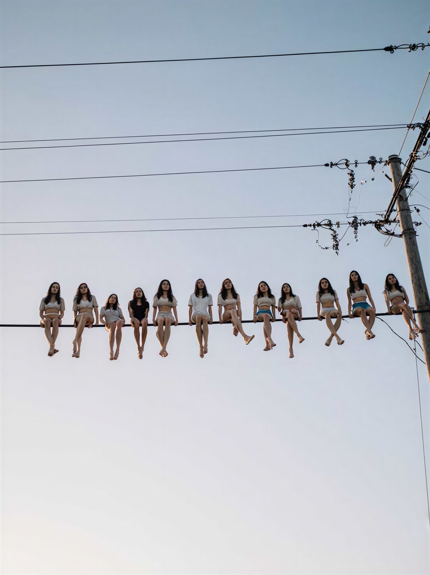 Young women on utility wire against a blue sky