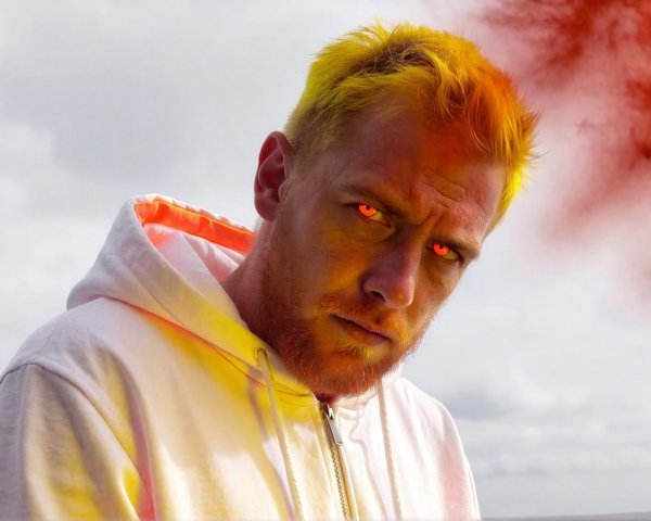 Close-up of a man with orange beard and pink eyes