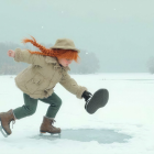 Joyful girl with red hair playing in the snow