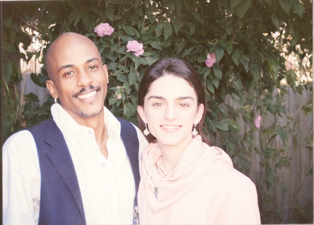 Smiling Couple Surrounded by Greenery and Roses