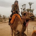 Person in Orange Space Suit Riding Camel in Desert