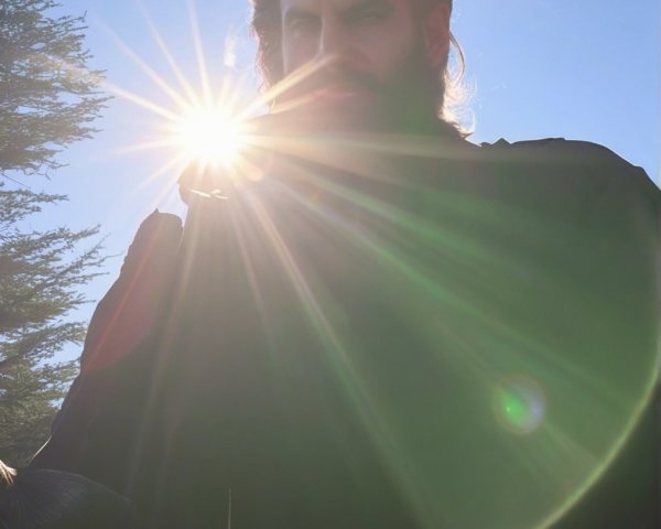 Person Outdoors with Lens Flare and Greenery Background