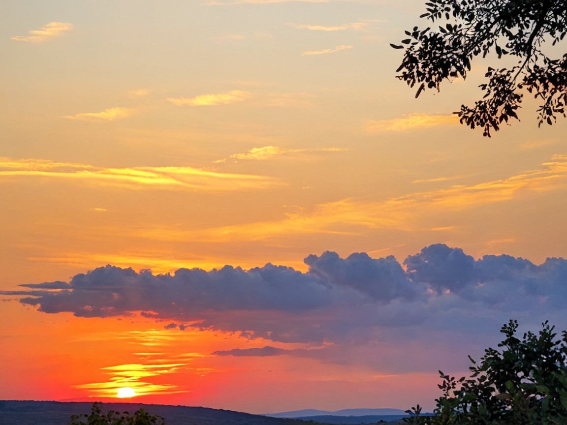 Vibrant Sunset with Silhouetted Clouds and Landscape