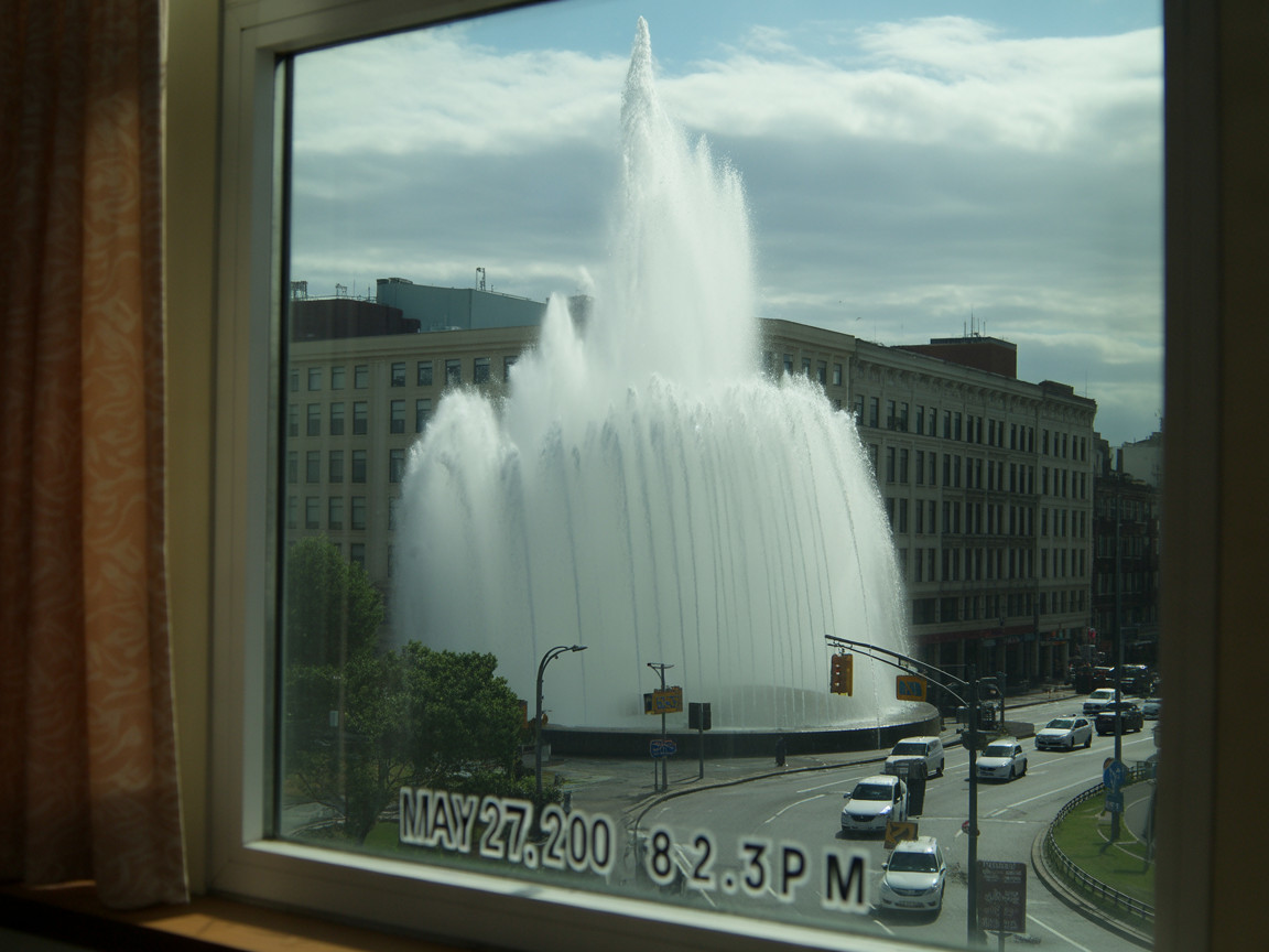 Fountain Display Against Urban Skyline and Traffic