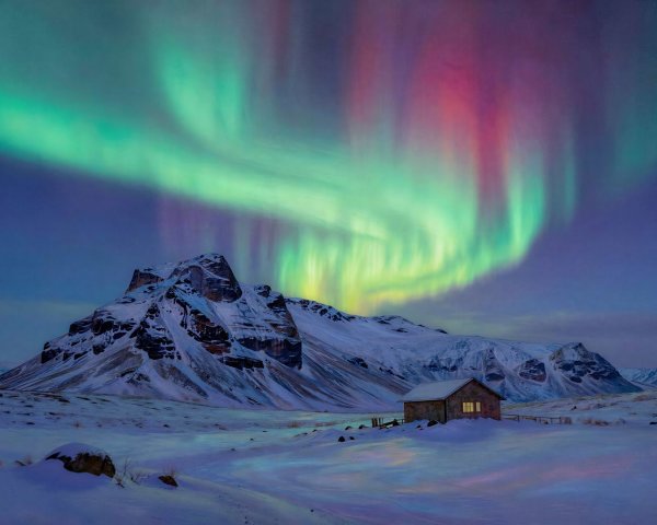 Aurora Borealis Over Snowy Mountains and Cabin