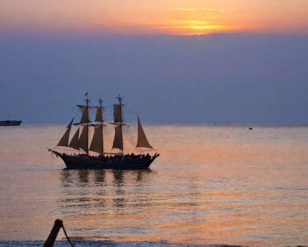 Tall Ship Sailing at Sunset on a Calm Sea
