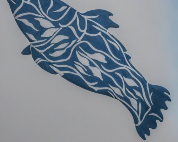 Wooden fish sculpture with white leaf patterns on blue