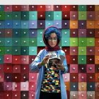Young woman with blue hair in front of colorful drawers